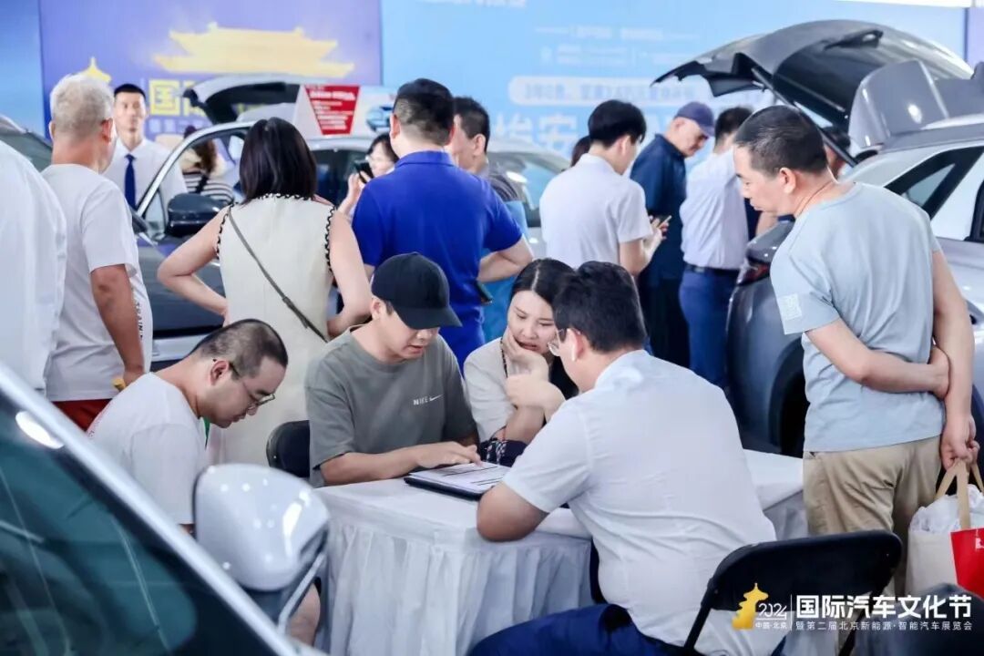 车展现场销售顾问与客户洽谈购车细节,建议提前做功课、问清优惠政策